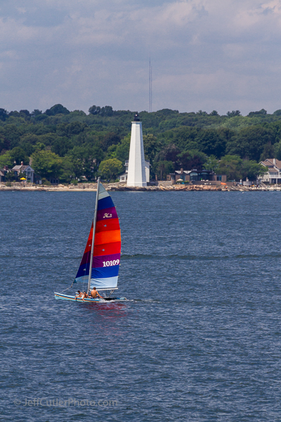 A sailboat goes in front of New London Harbor Light.